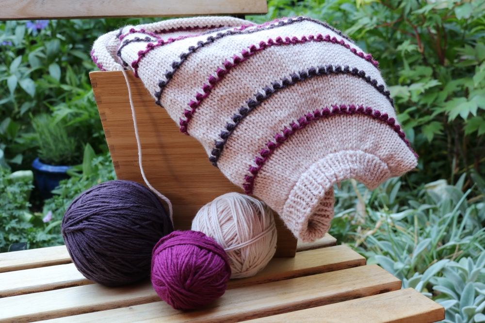 started striped pullover and wool balls on a small table in the garden